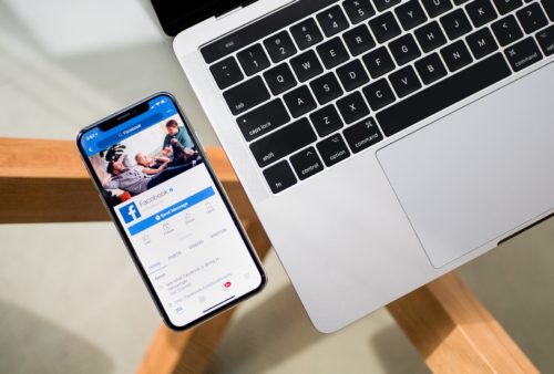 Telefon z włączonym Facebookiem leżący na stole